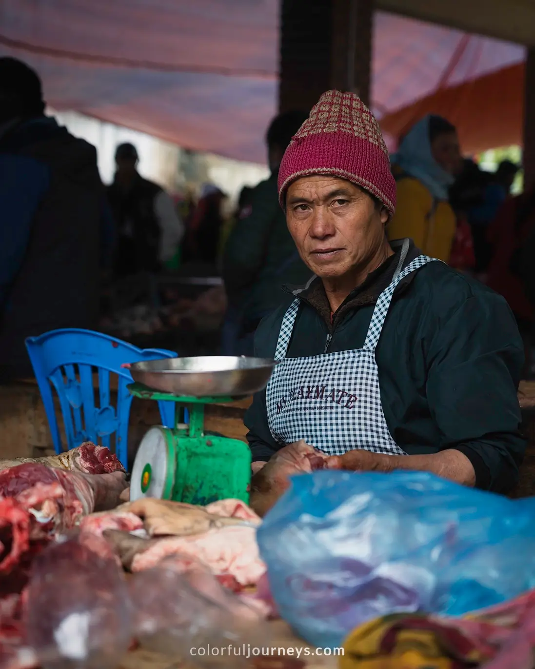 A man looks at the camera while selling meat at Bac Ha market, Vietnam