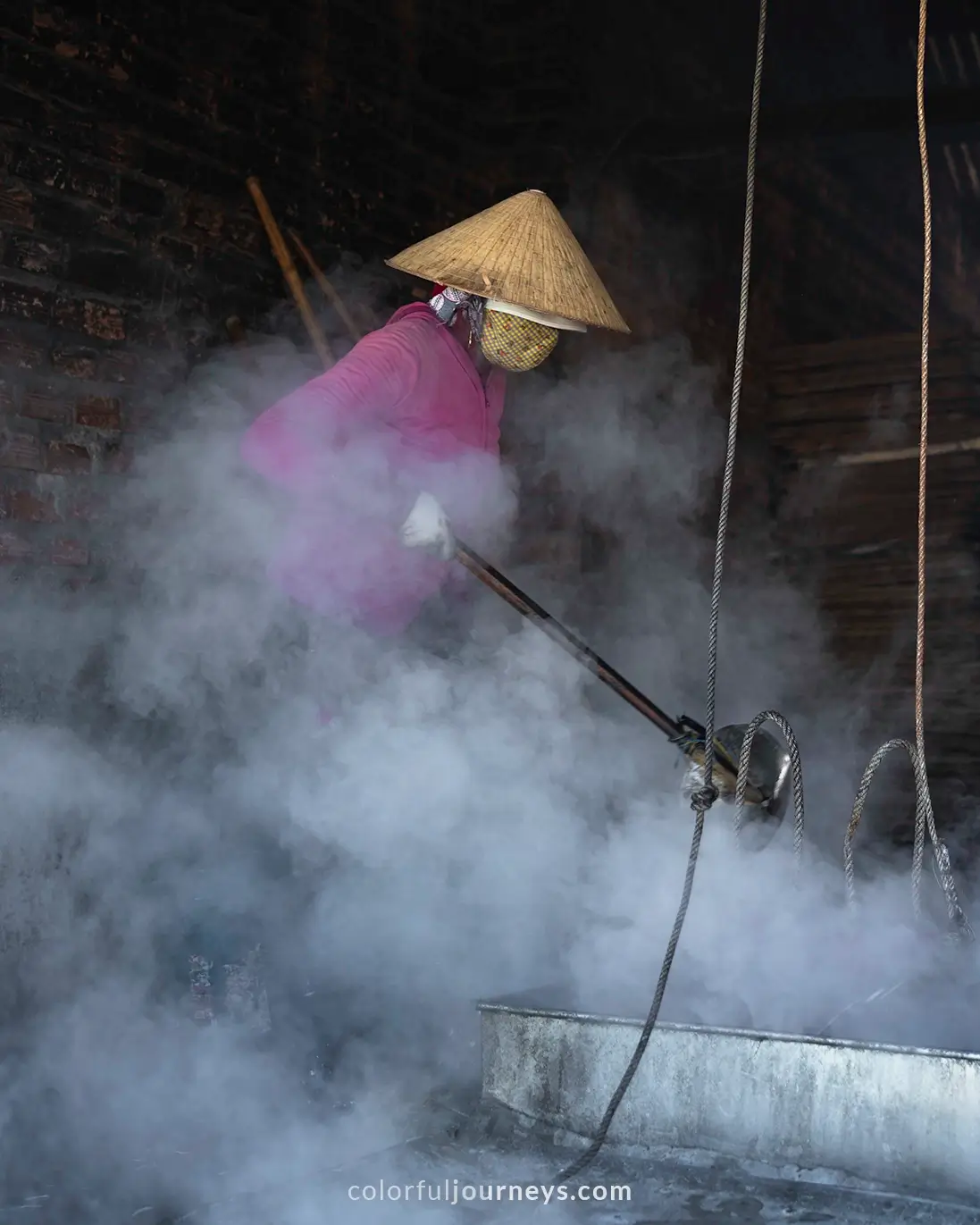 A woman is surrounded by smoke from cooking anchovis in Phu Yen, Vietnam