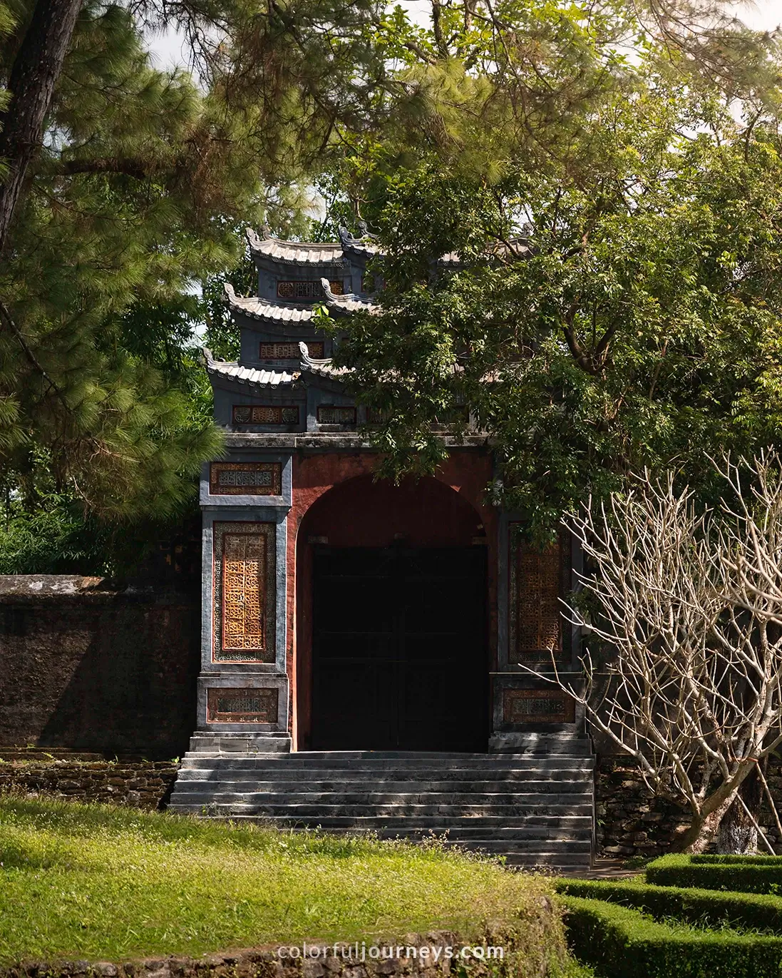 A gate surrounded by trees at the Tu Duc tomb complex in Hue, Vietnam