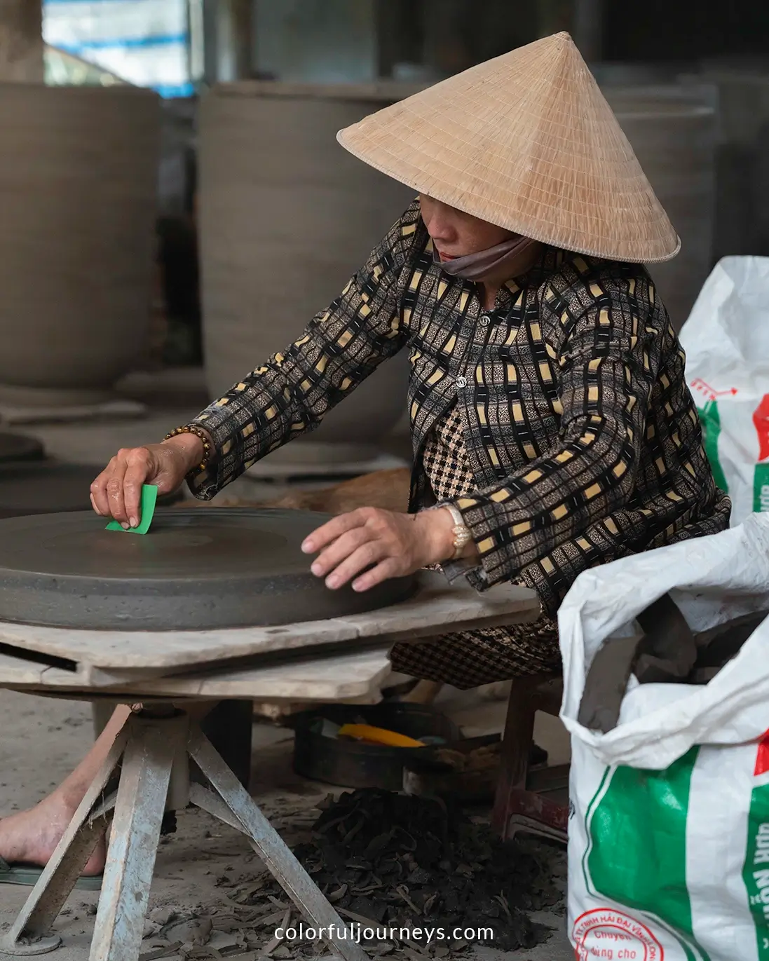 A woman wearing a Non La makes pottery in Vinh Long, Vietnam
