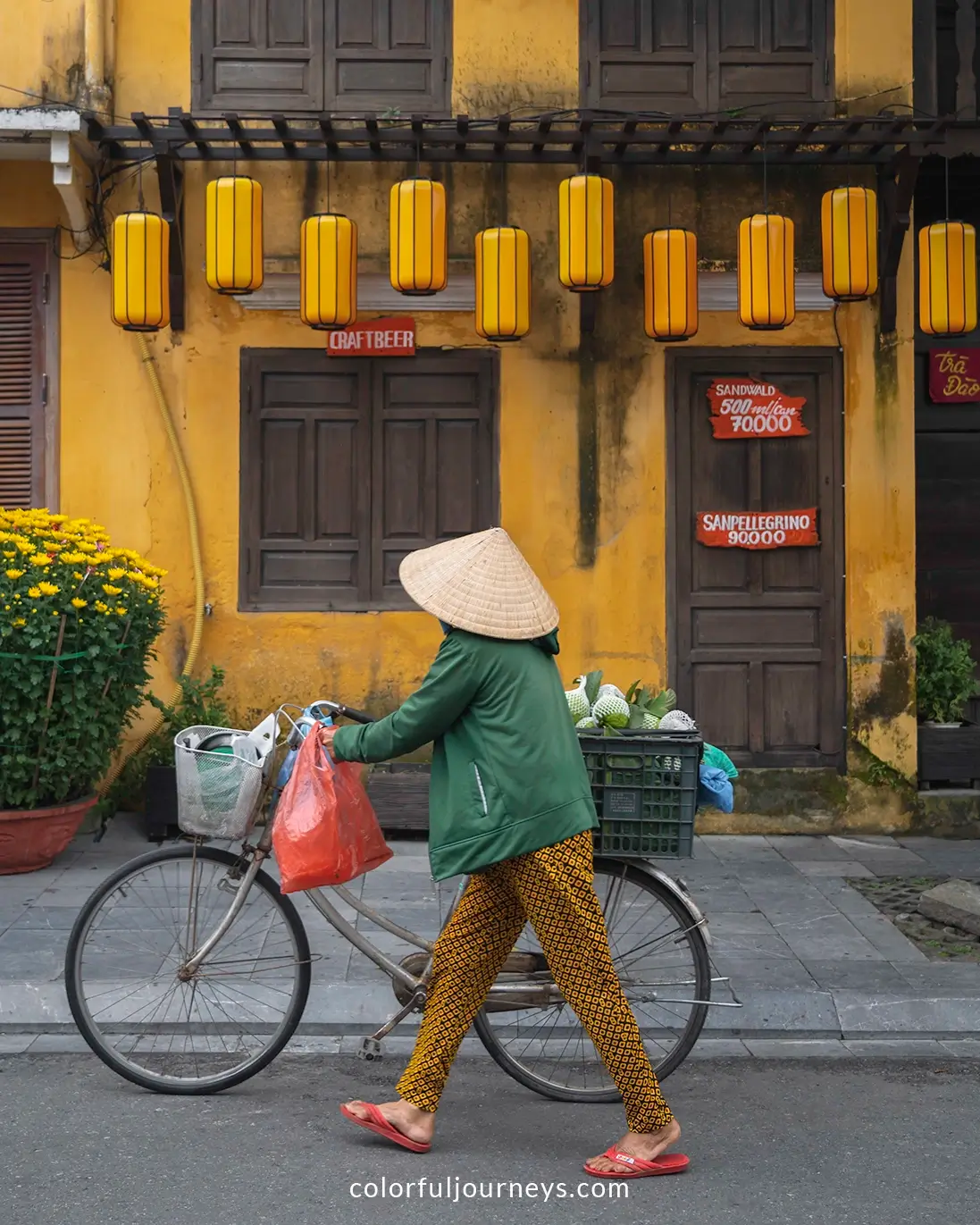 A woman walks with her bicycle in Hoi An, Vietnam