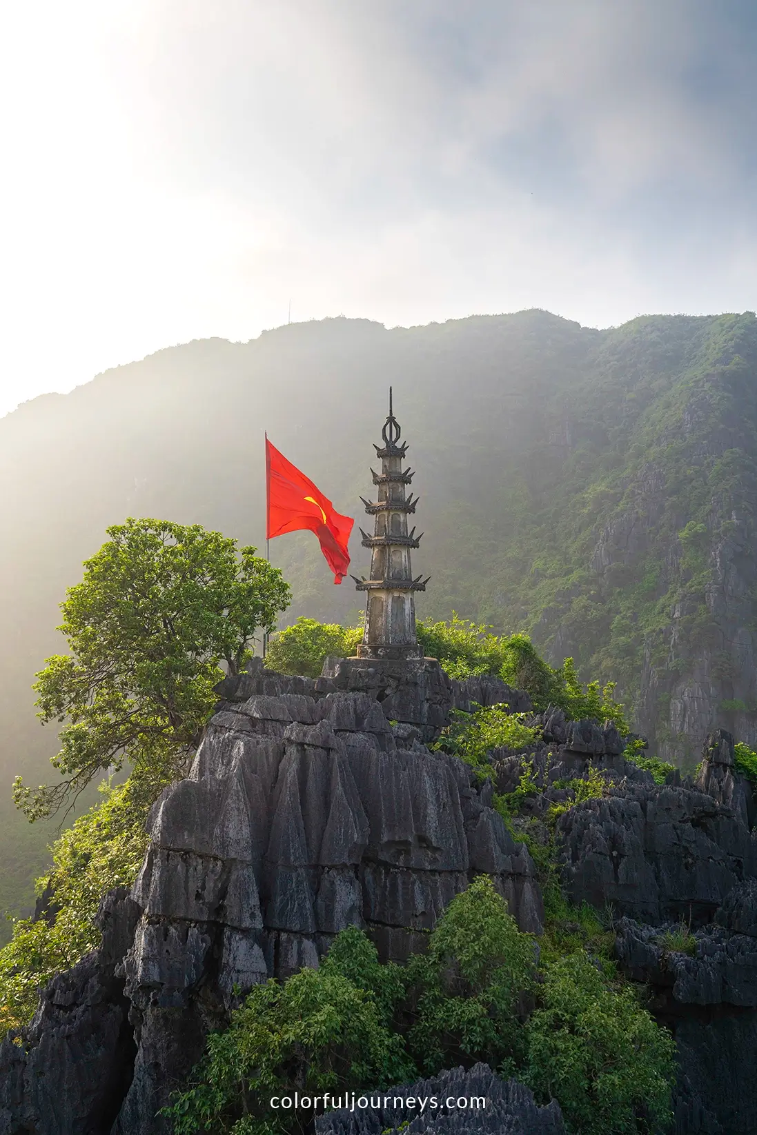 A pagoda with a Vietnamese flag at Hang Mua viewpoint in Ninh Binh, Vietnam