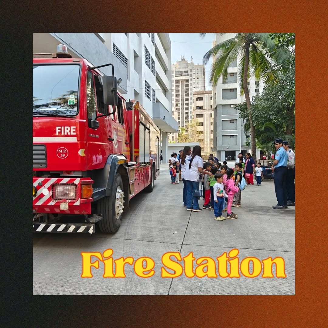 Children wearing firefighter hats, standing next to a fire truck