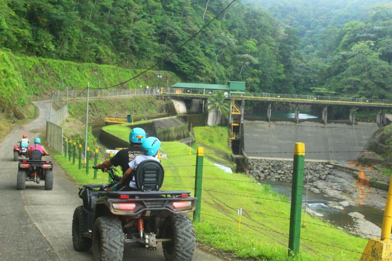 Vista de una represa hidroeléctrica y formaciones de roca basáltica con agua clara y vegetación tropical.