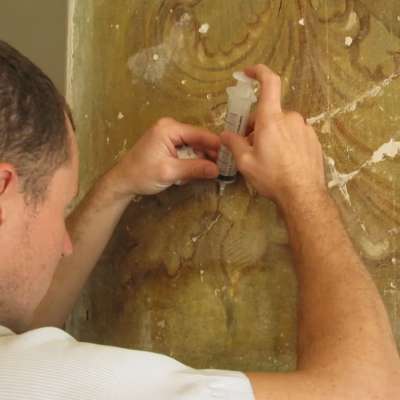Conservators focused at work on the mural 