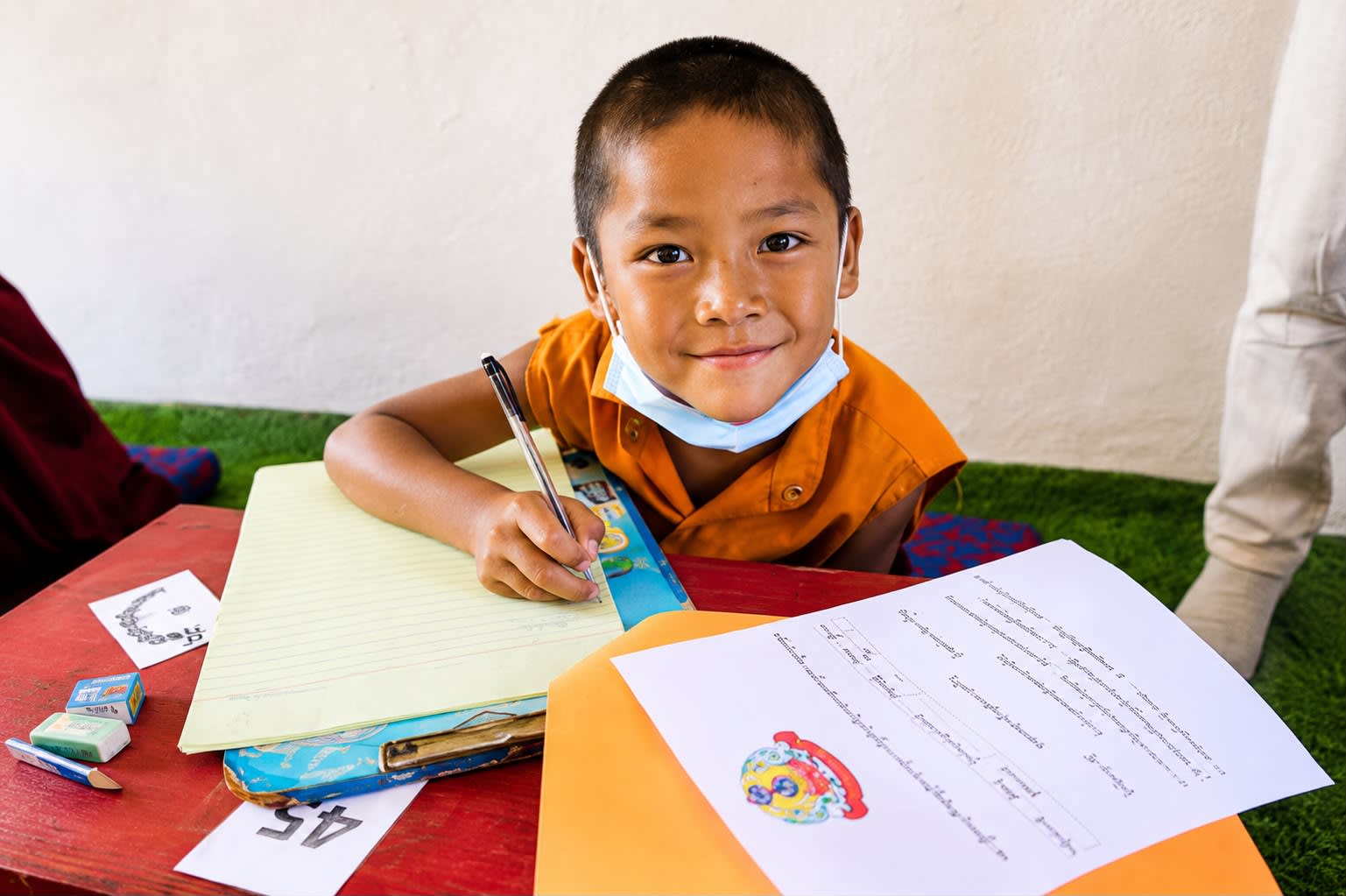 A group of young Tibetan monks in traditional maroon robes engaged in a lively debate in an open-air monastery courtyard