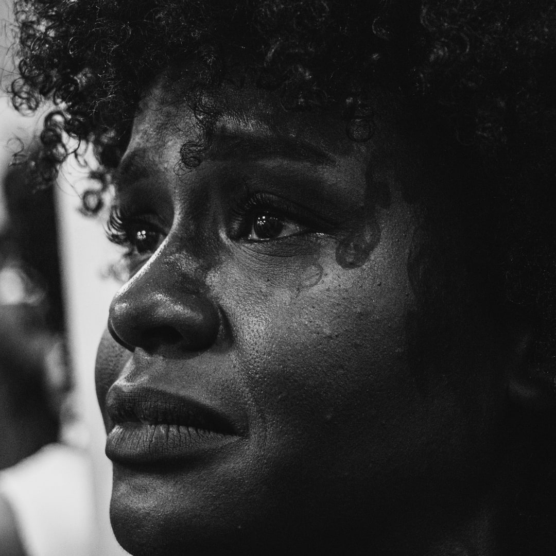 A black and white image of a woman with an afro, reflecting deep emotions of family ties, friendship, and trust issues.