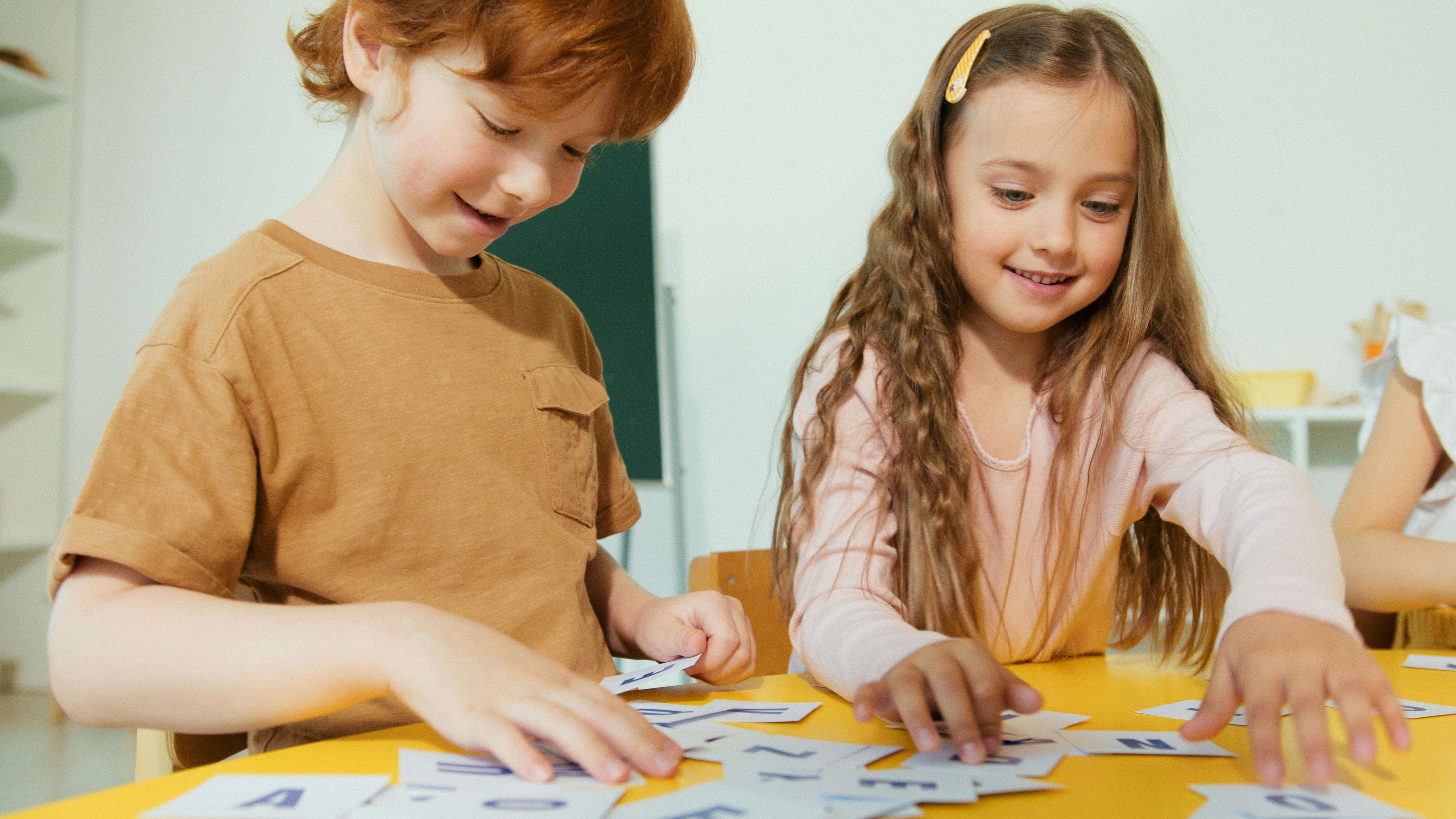 Two children sitting at a table and happily sorting through alphabet flashcards—captures the fun, hands‑on essence of flashcard learning.
