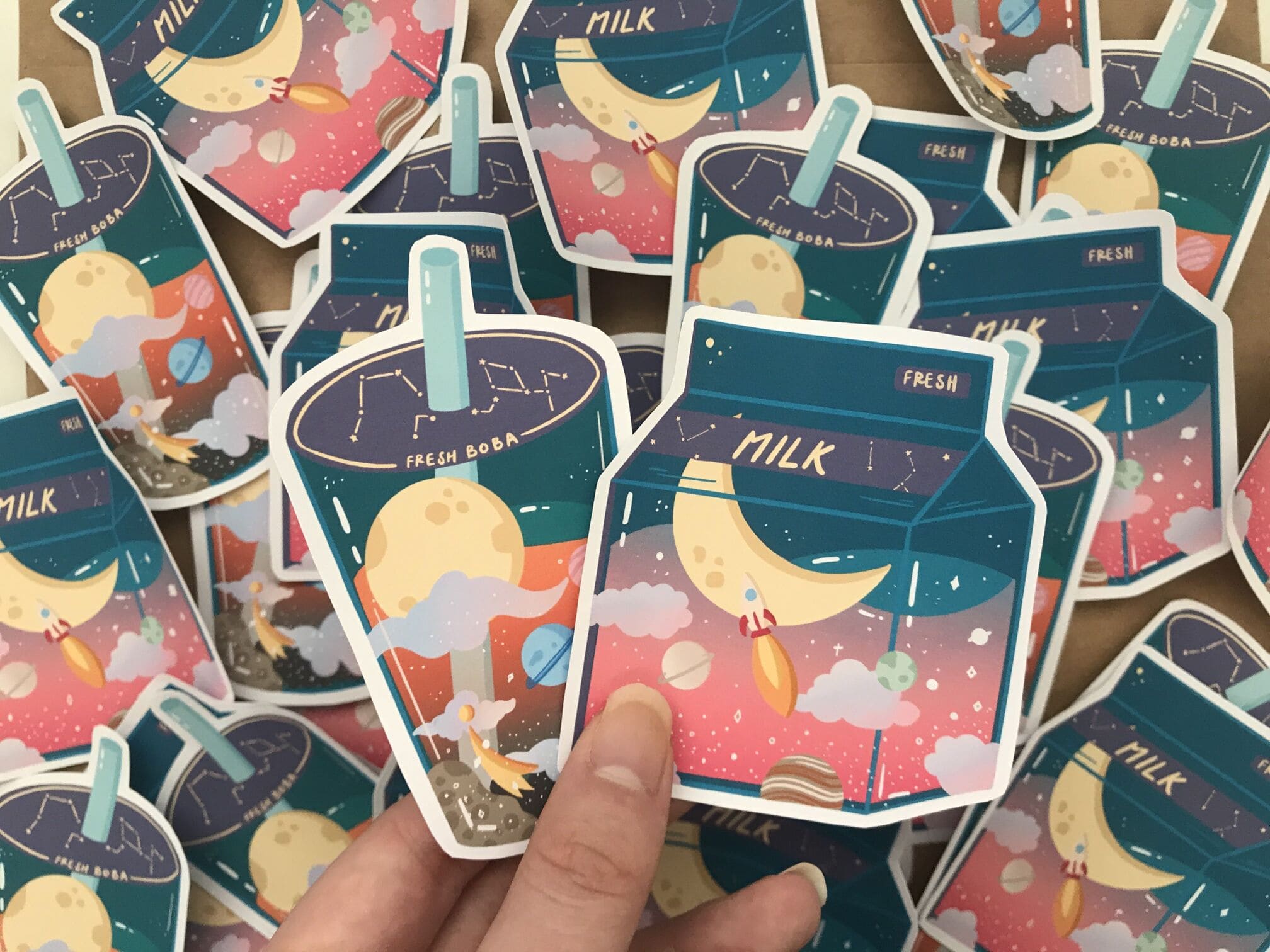 handmade stickers showing see-through boba and milk containers with space designs in them