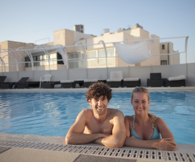 Man Sitting on Swimming Pool Besides a Lady in Blue Bikini (How to Become a Water Aerobic Instructor?)