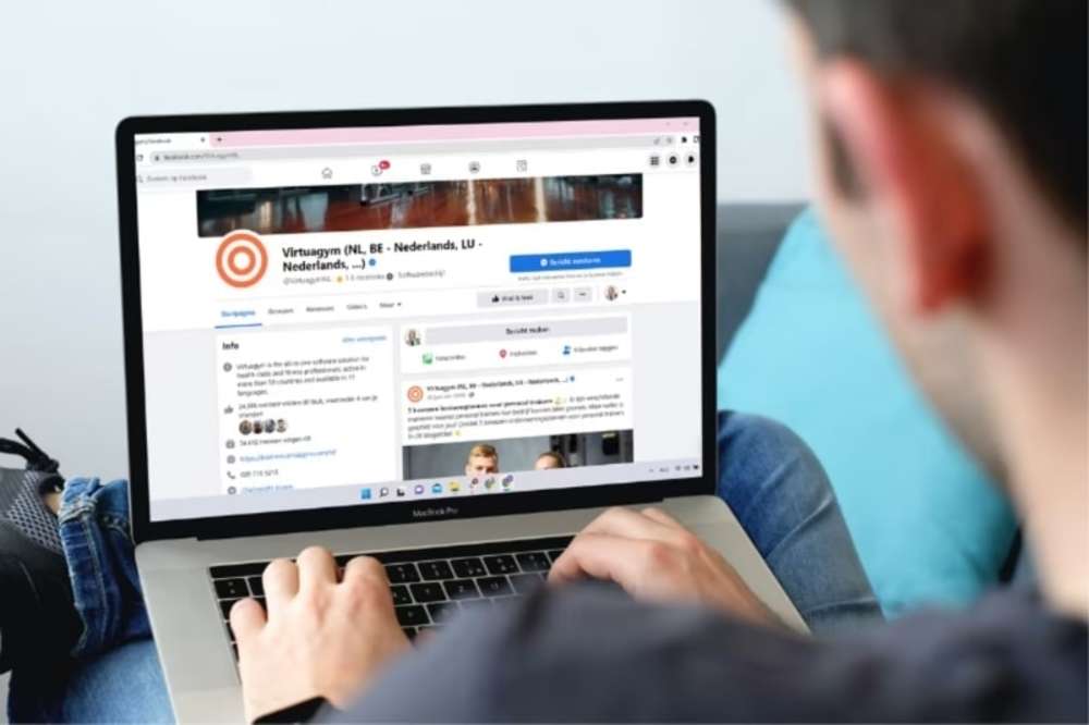 Person using a laptop, viewing the Virtuagym Facebook page