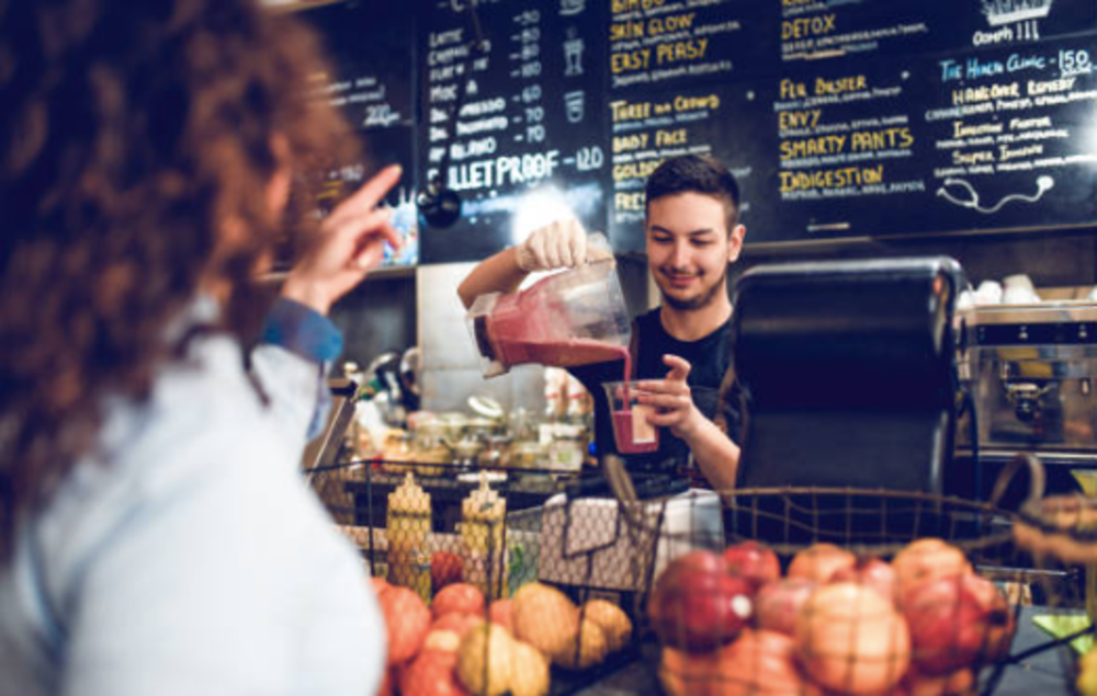 Employee working at smoothie bar in gym serving clients