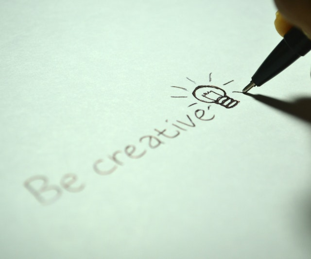 A pen wrote on the paper ‘Be creative’ with light bulb drawing