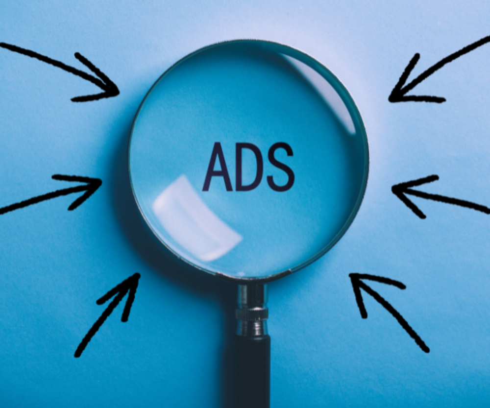 Eine Lupe, die auf das Wort "ADS" gerichtet ist, mit Pfeilen, die auf das Wort zeigen, auf blauem Hintergrund.