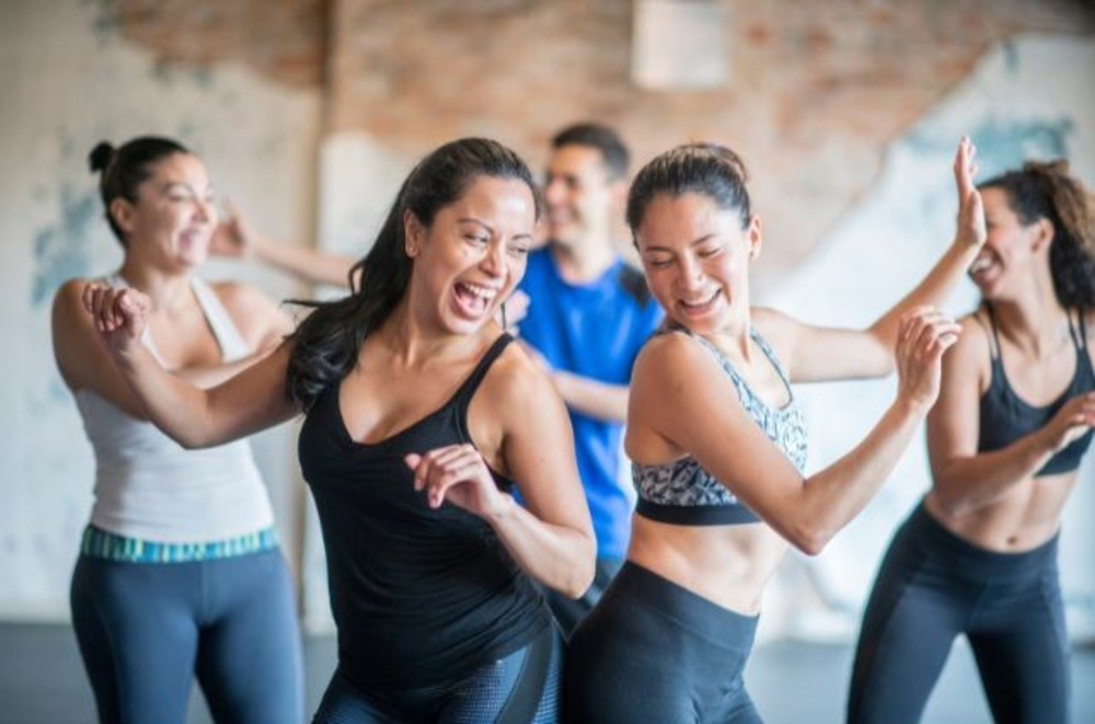 Group of people dancing and laughing together in a dance fitness class.