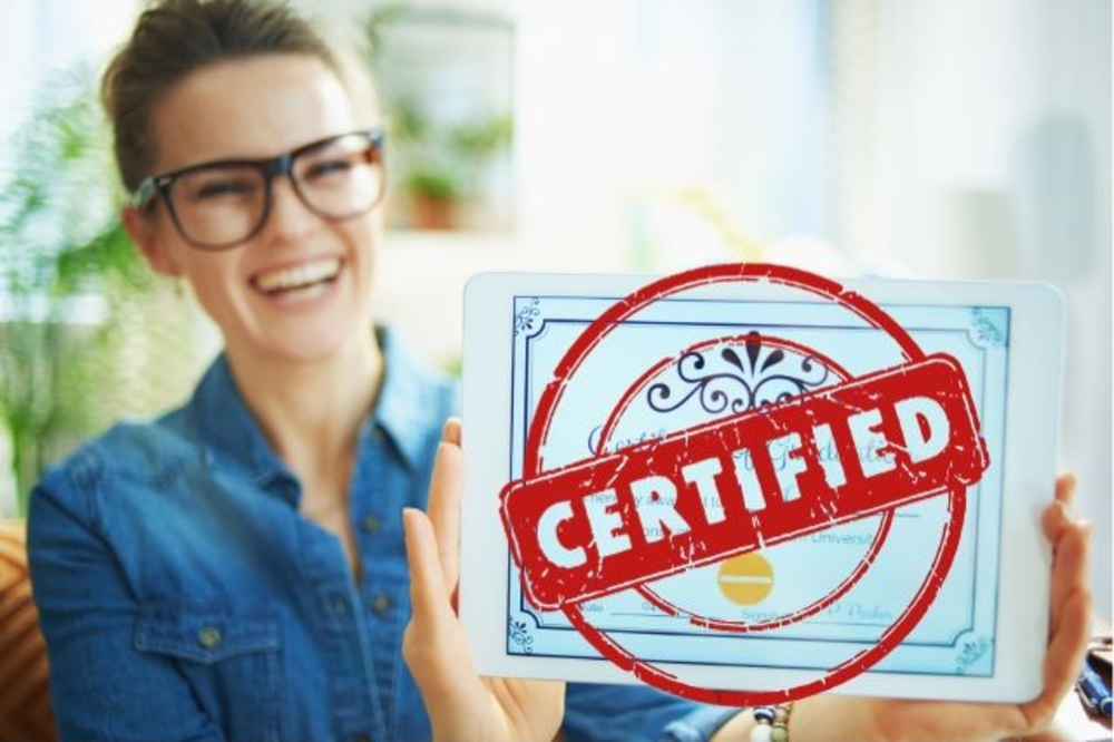 Woman smiles and holds the paper saying Certified