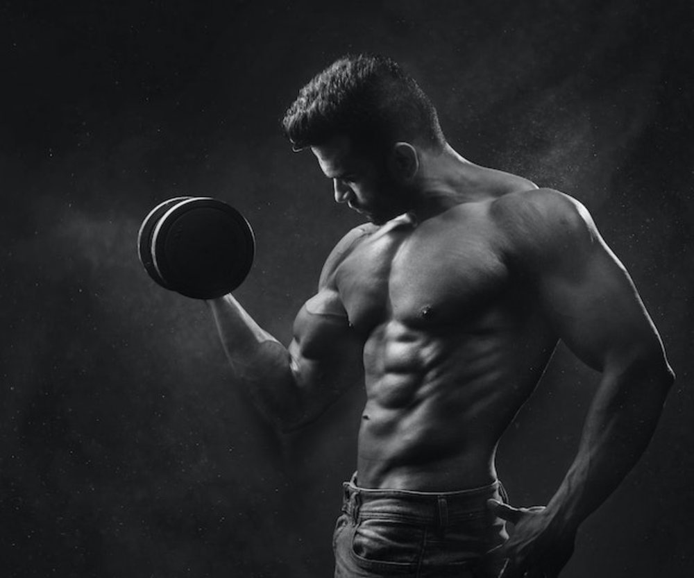 Black white picture of trained man standing with dumbbell in his hand