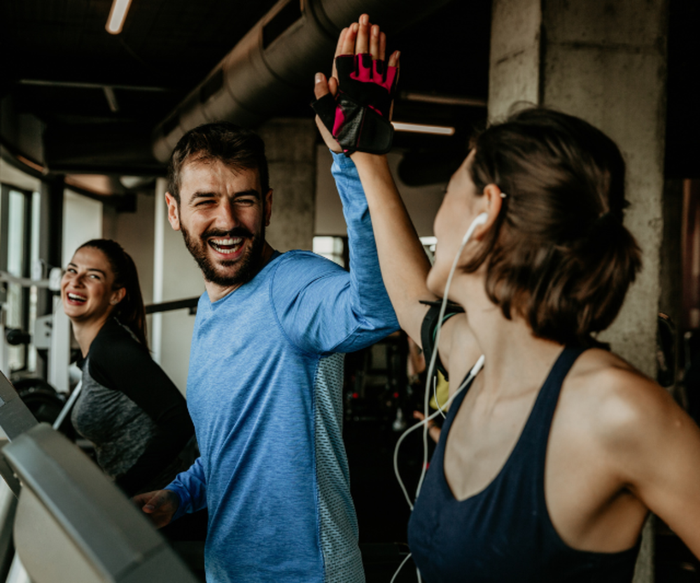 A group of people high-fiving each other in a gym setting, signifying teamwork and fitness enthusiasm.