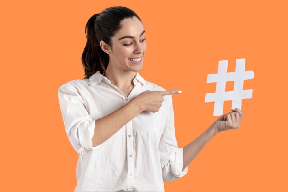 Eine Frau zeigt auf ein großes Hashtag-Symbol, das die Verwendung von Hashtags für Social-Media-Inhalte hervorhebt