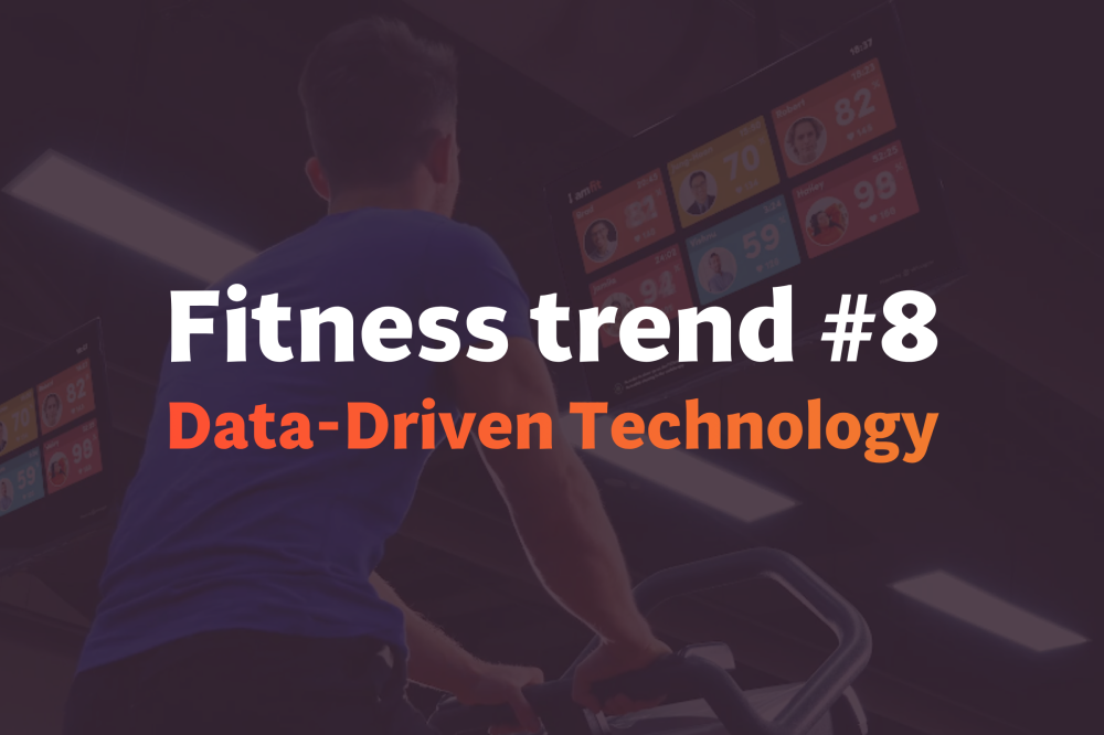 Trainer in orange shirt analyzes data on a laptop, connecting health behaviors with current sports medicine reports.