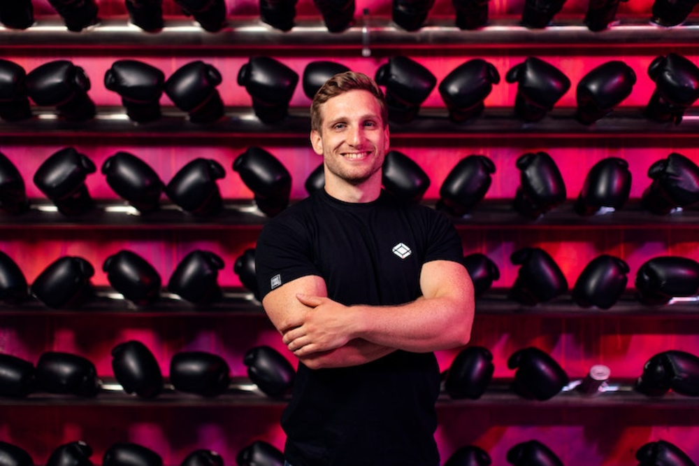 Boxing gloves on the background and personal trainer stands in front