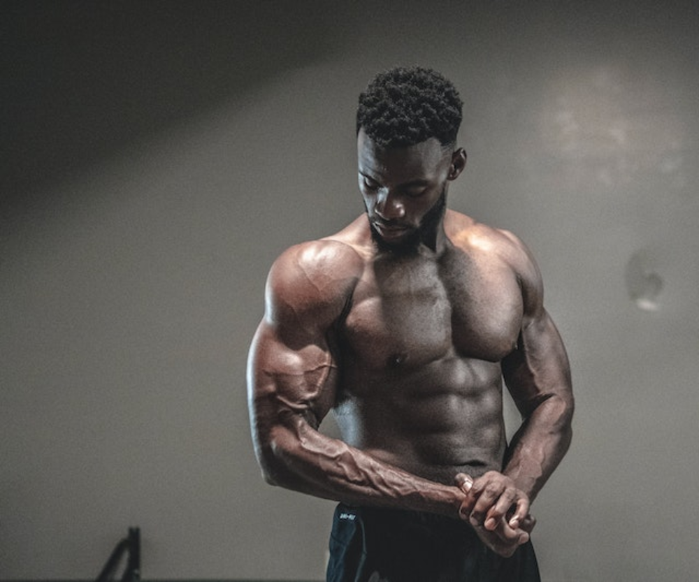 A muscular man focusing intently while adjusting his wrist wraps, preparing for a workout in a gym environment.
