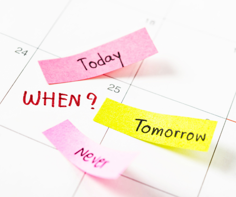 A calendar with colorful sticky notes reading "Today," "Tomorrow," and "Never," with the word "WHEN?" written in red ink.