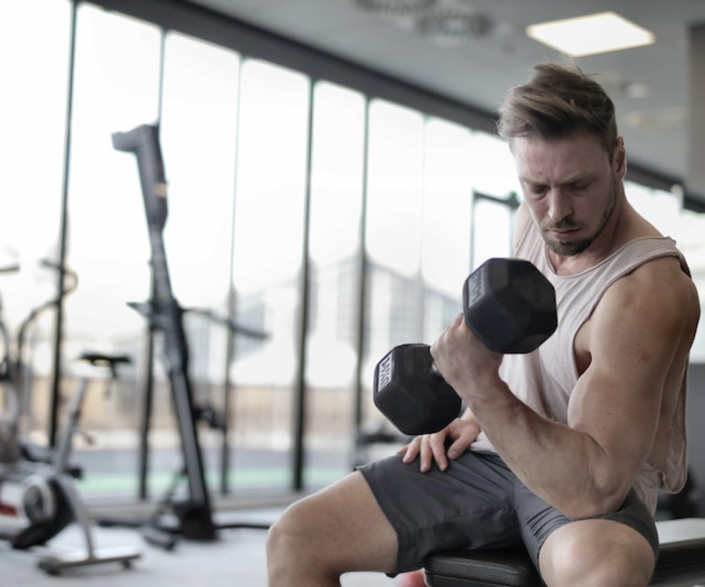 Man is doing exercise with dumbbell in the gym