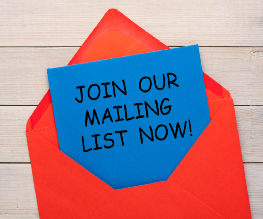 Eine blaue Karte mit dem Text &quot;JETZT IN UNSEREN E-MAIL-VERTEILER EINTRAGEN!&quot; kommt aus einem roten Umschlag und liegt gegen einen hölzernen Hintergrund.