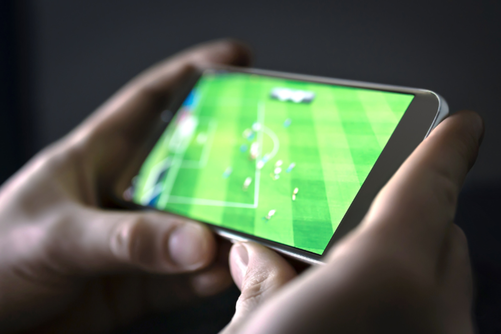 Hands holding a phone showing a live soccer match.
