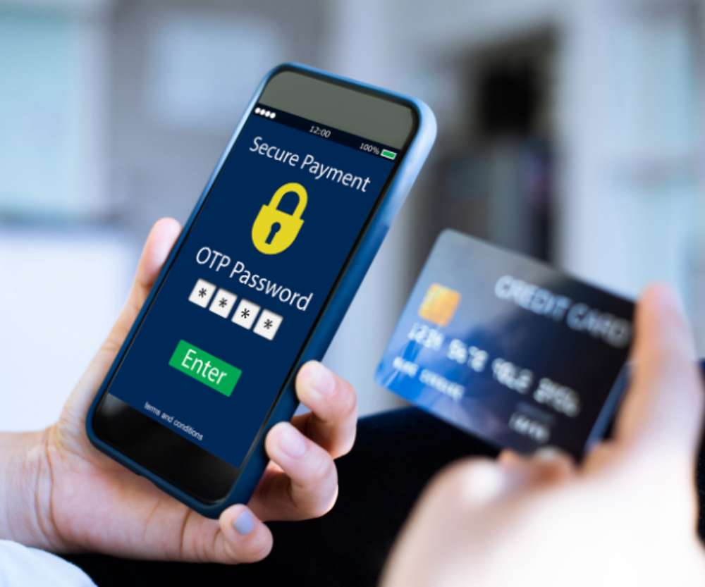Eine Person verwendet ein Smartphone, um eine OTP für eine sichere Zahlung einzugeben, während sie eine Kreditkarte in der anderen Hand hält.