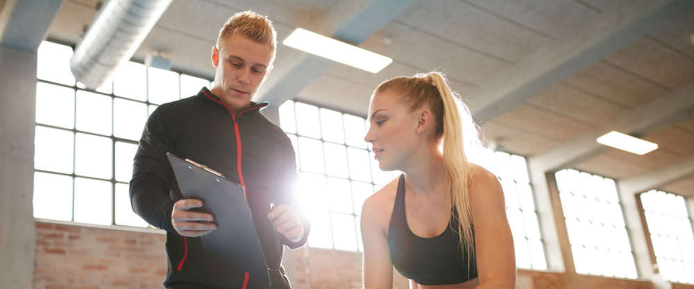 Personal Trainer Making An Exercise Plan For Young Woman