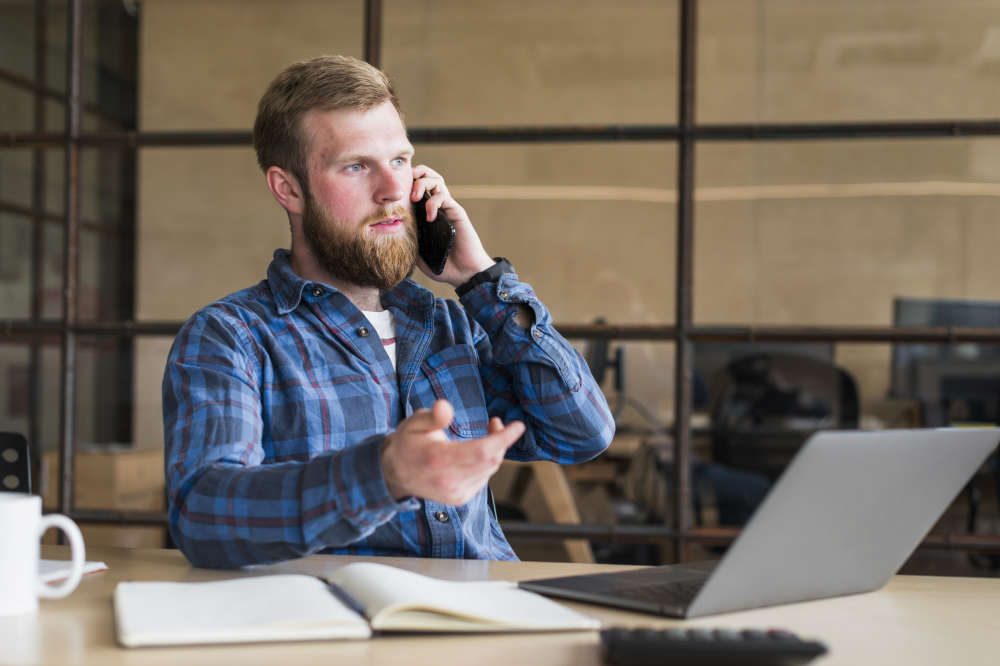 Serious bearded man talking on cellphone and working