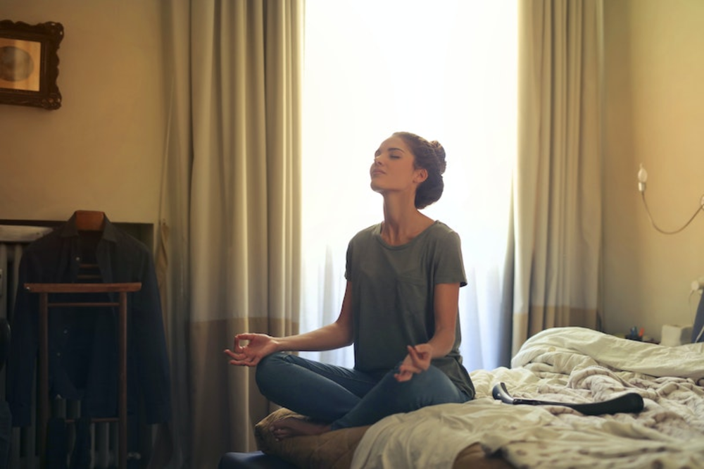 A woman sitting on a bed meditating