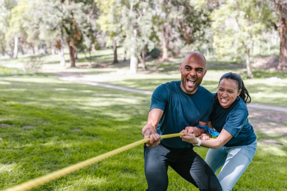 A man and a woman playing tug of war outdoors