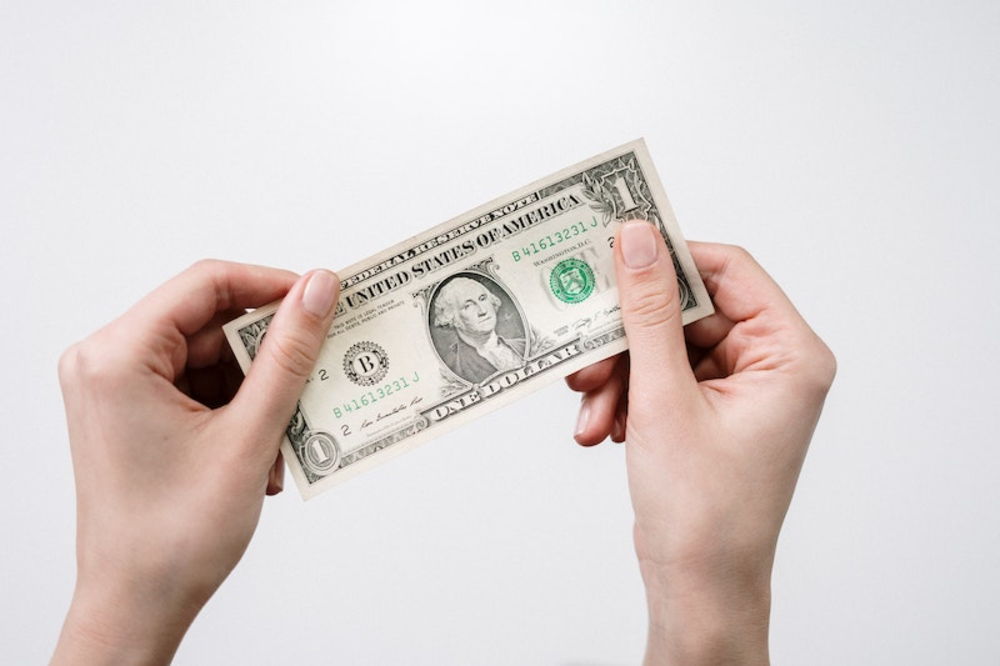 A bill of one dollar held in two hands