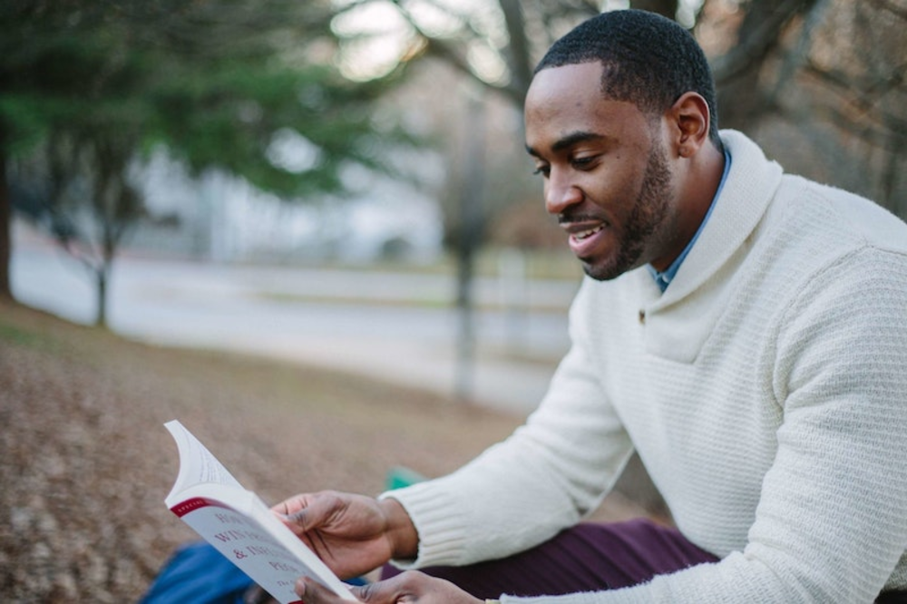 A man reading a book while sitting outdoors