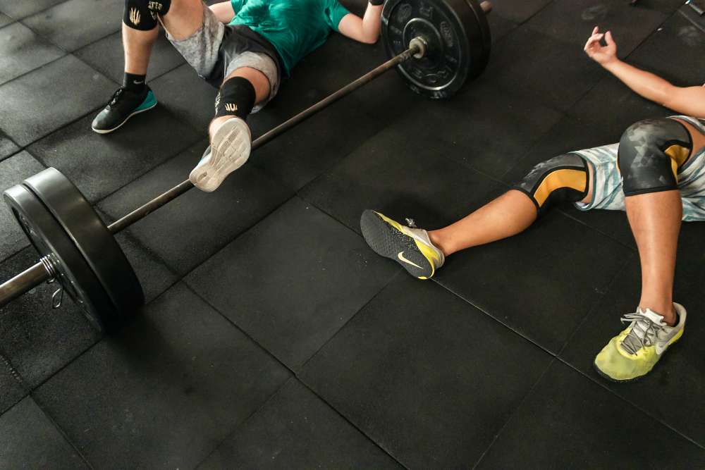 Deportistas descansando en el suelo tras hacer sesiones de peso en el gimnasio