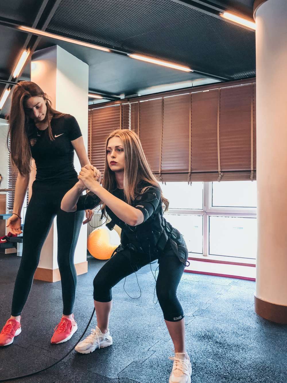 Woman is doing squats under the guidance of personal trainer