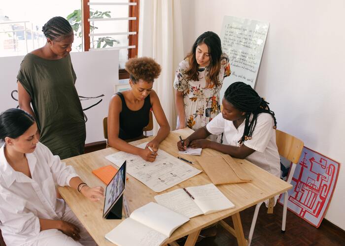 Cinco mujeres escribiendo el plan y discutiendo algo en la oficina