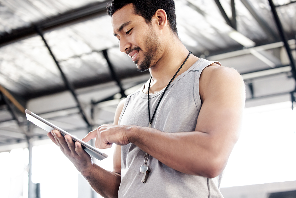 Fitnesstrainer sieht auf dem Tablet-Bildschirm aus