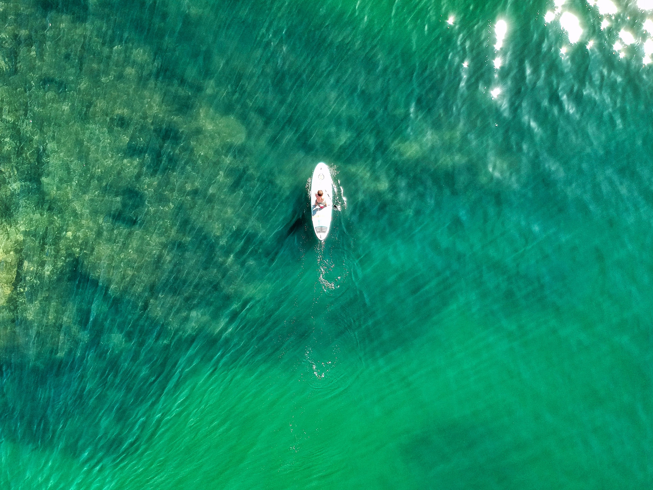 Blick von oben auf einen Mann schwimmen auf einer Brandung durch das grüne Wasser Meer