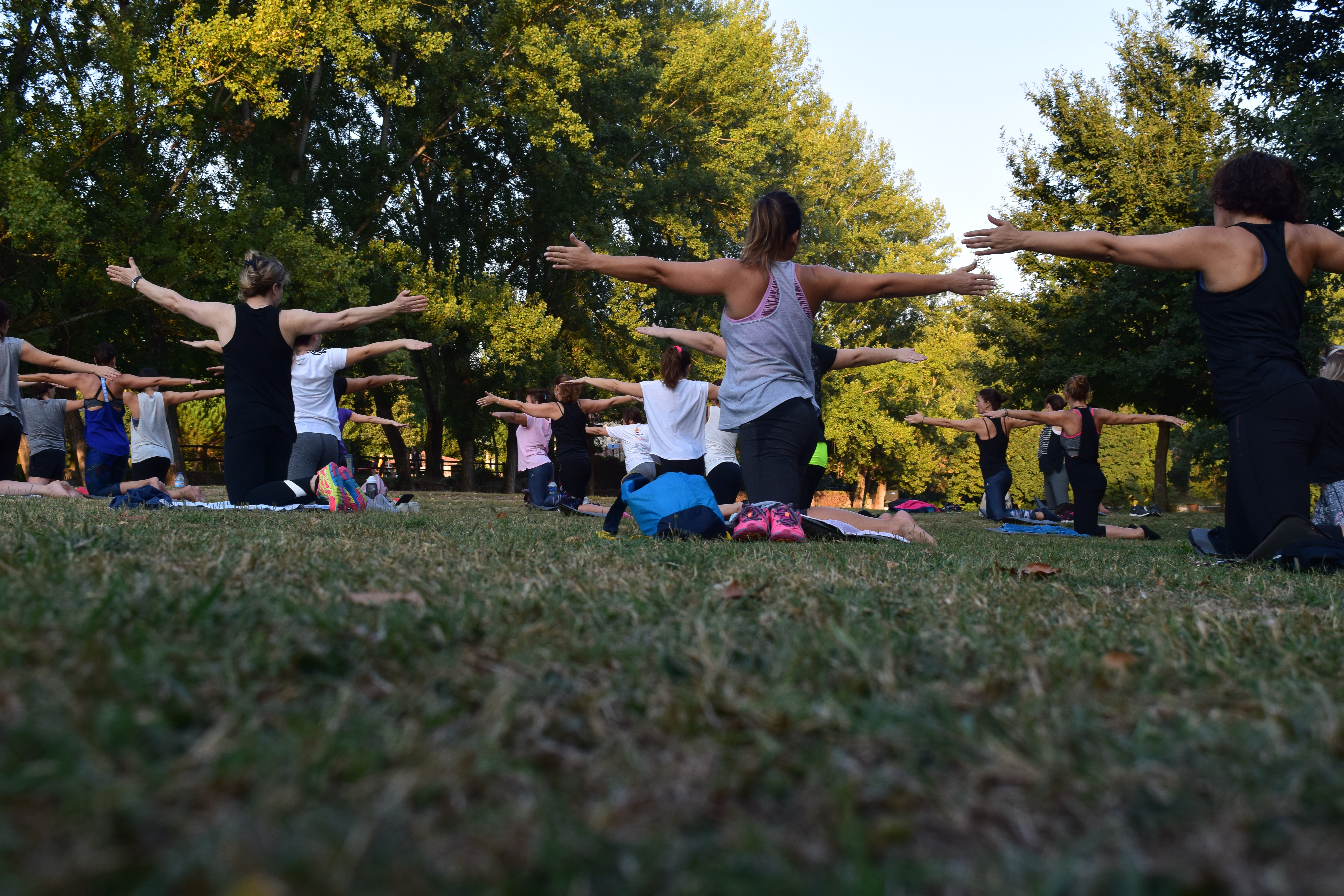 para que sirve el yoga en las mujeres - mujeres en masa liberando toxinas y practicando ejercicios de yoga al aire libre en clase