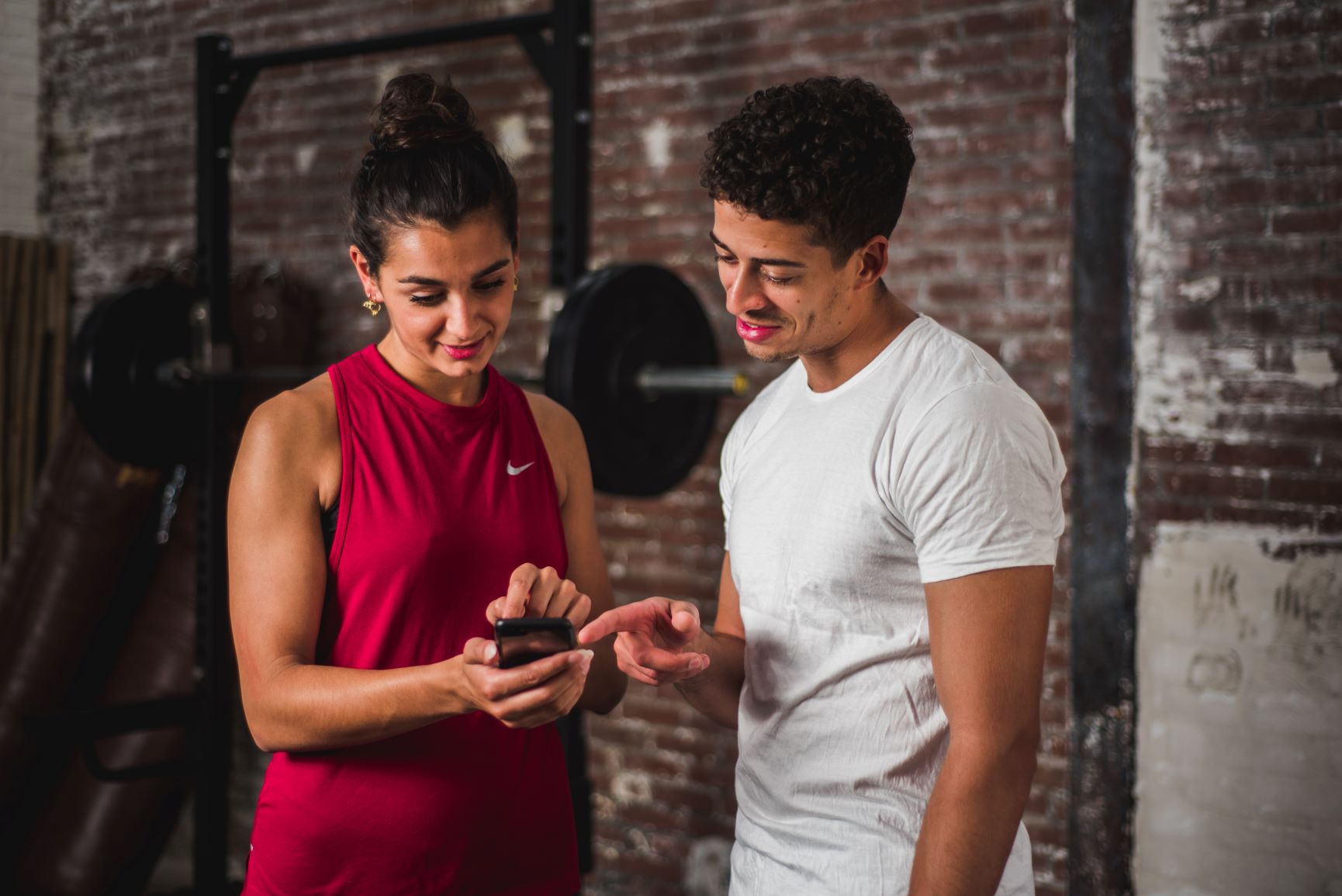 Man en vrouw wijzen aan de telefoon met Virtuagym-app erop