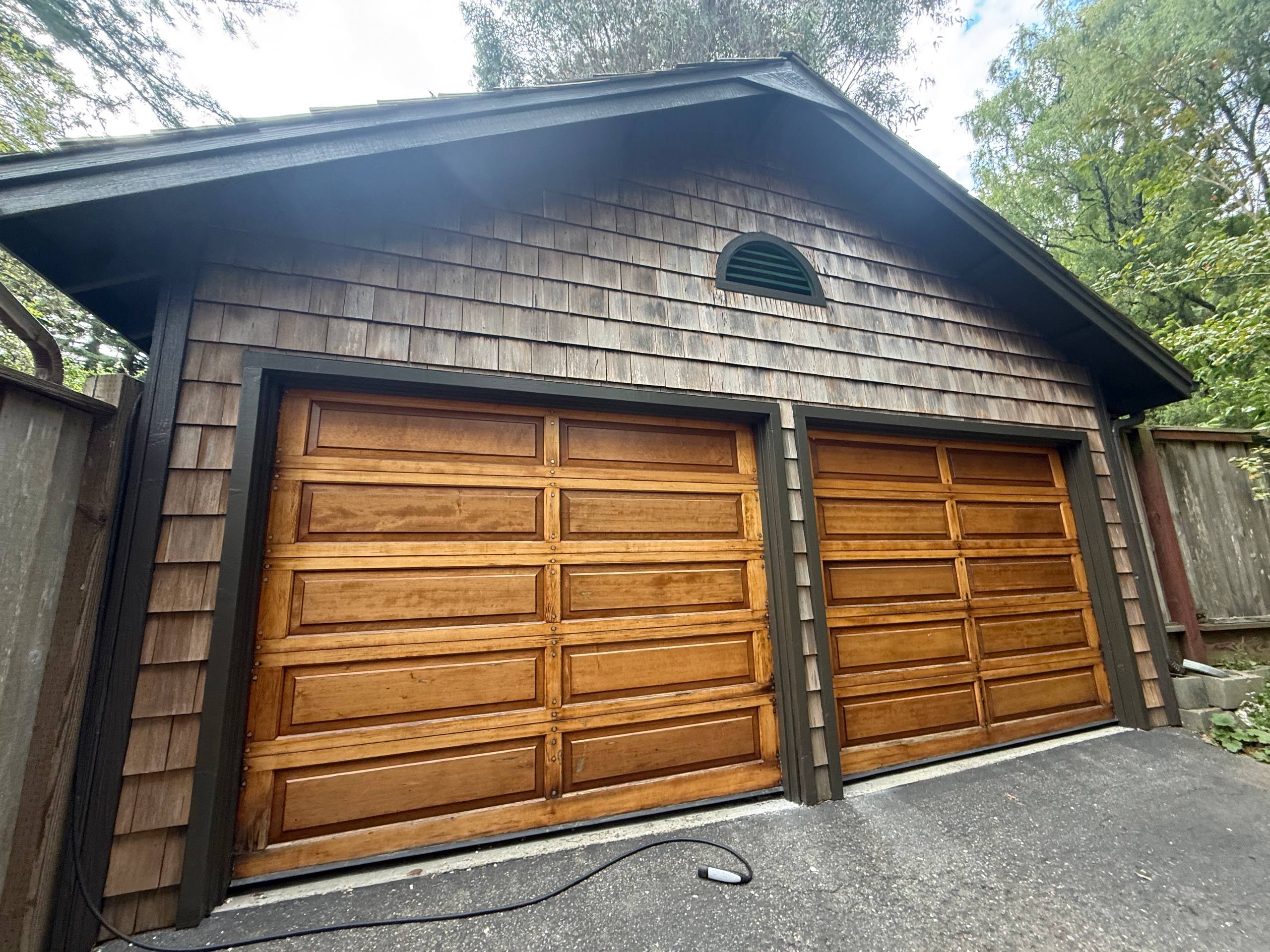 Finished garage façade with crisp dark trim around wood doors and gable.