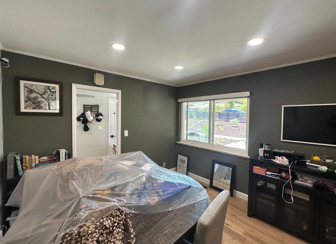 Finished dark accent wall in the living area with light ceiling, trim and window details; a private portrait is blurred.
