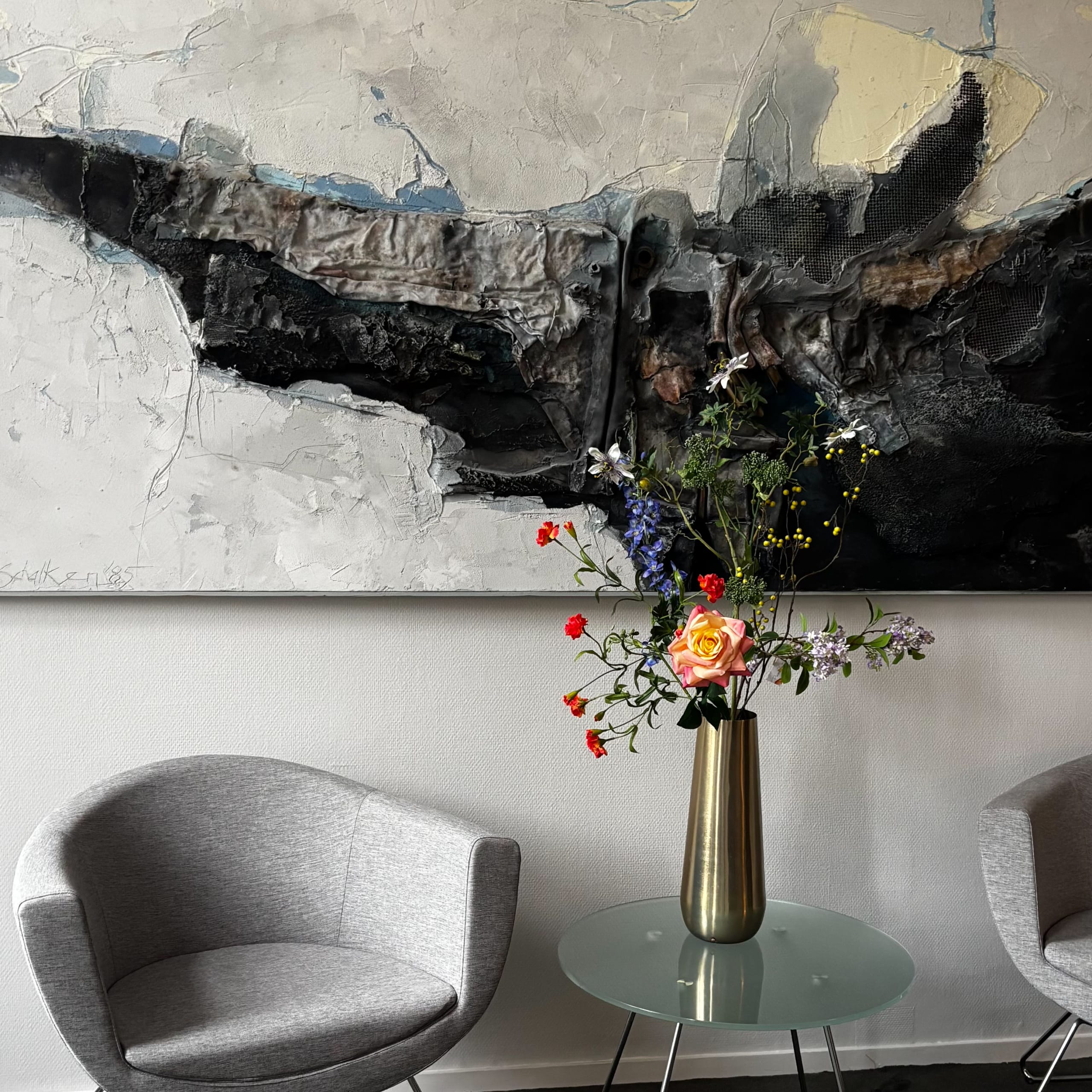 Kunstbloemen boeket FlowerDutchess met roos, blauwe bloemen en oranje accenten in gouden vaas op kantoor tafel met moderne kunst