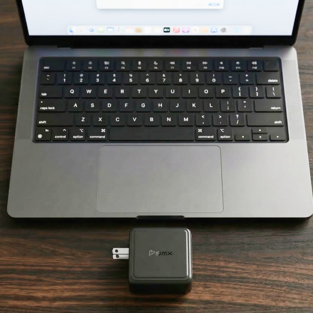 GaNsta next to a laptop, compact enough to disappear in a bag