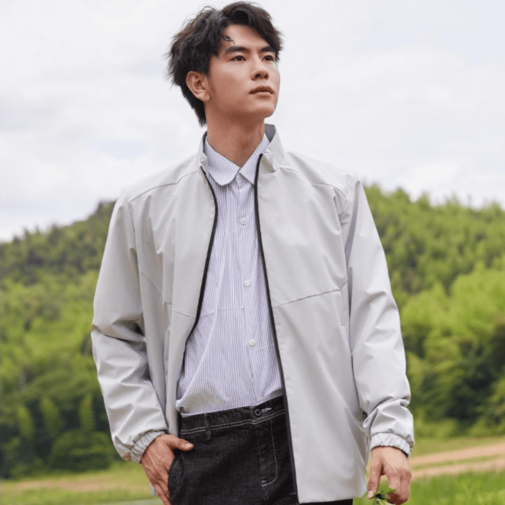 Stylish young man in a serene countryside setting, exuding calmness and connection with nature.