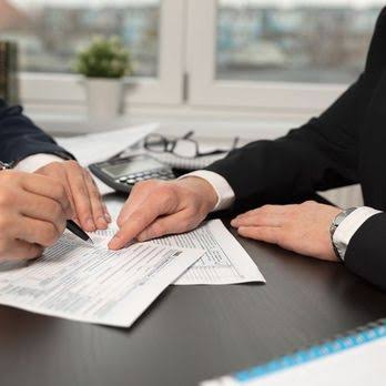 Two professionals reviewing and signing loan documents at a desk
